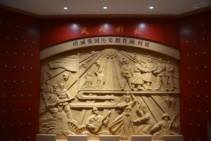 Large sculpted relief mural depicting historical figures, mounted on a museum gallery wall