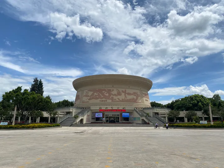 Round drum-shaped museum building with relief carvings under a blue sky