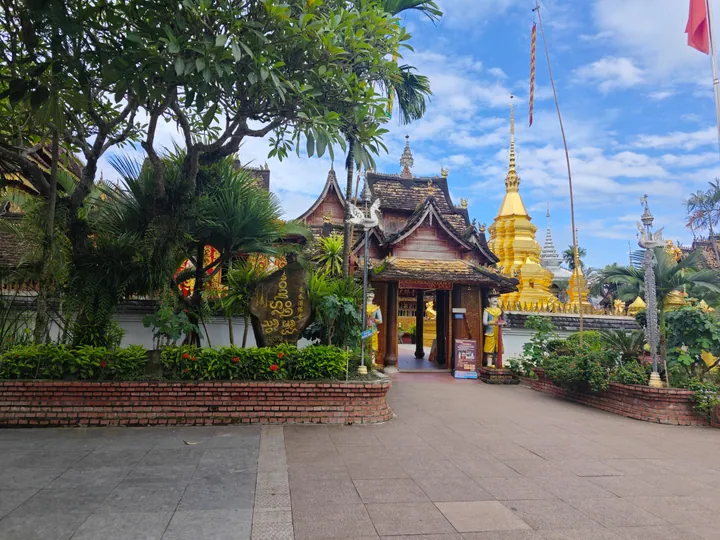 Ornate wooden temple gateway with a golden stupa spire behind it