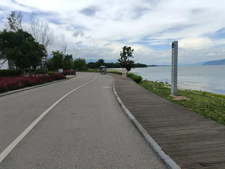 Wooden boardwalk along Erhai Lake with an inscribed stone marker