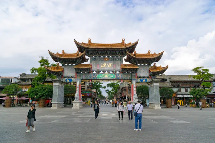 Ornate multi-tiered gate arch over a pedestrian street at Guandu Old Town