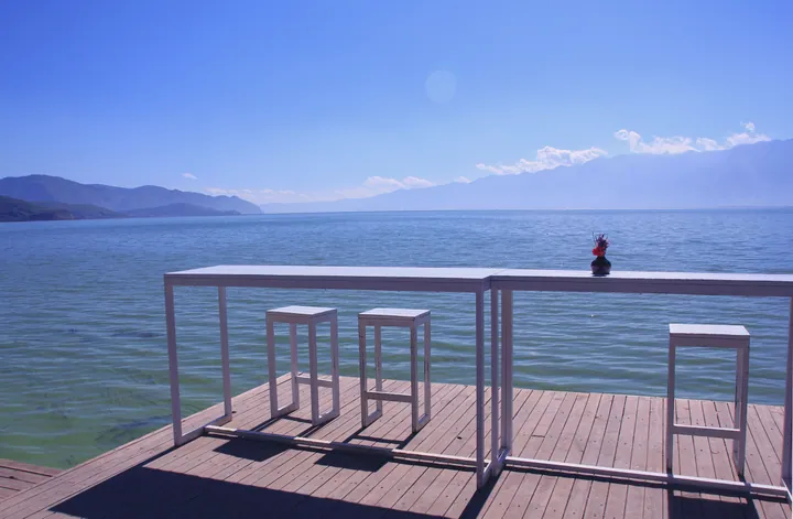 Tables and chairs on a wooden deck beside Erhai Lake at Shuanglang