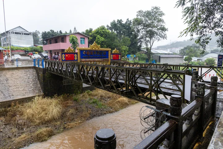 Steel truss bridge with a China border marker sign, seen on a rainy day