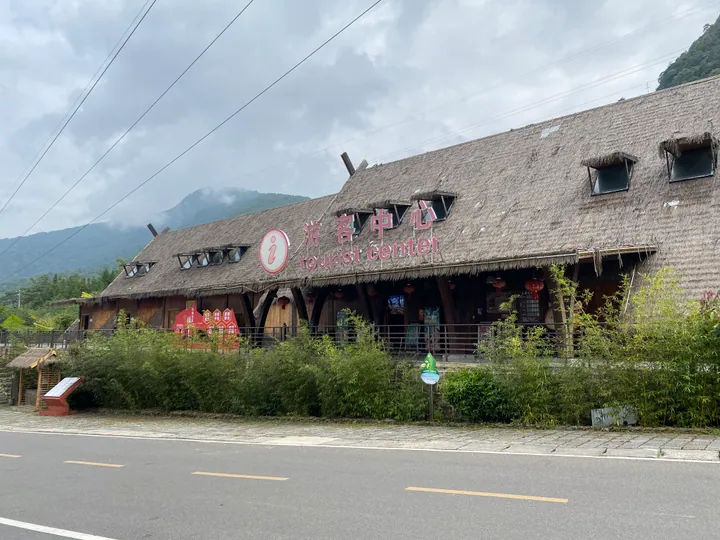 A large thatched-roof building signed 'Tourist Center' at the entrance to Om Din Village
