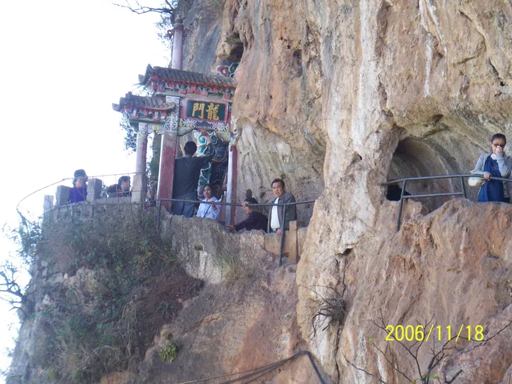 Stone archway carved into a cliff labelled Dragon Gate, with visitors