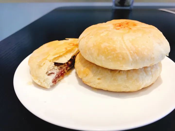 Two flaky rose-filled pastries on a plate, one cut open showing the filling