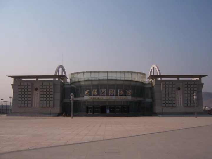 Modern museum building with a glass rotunda entrance and open plaza