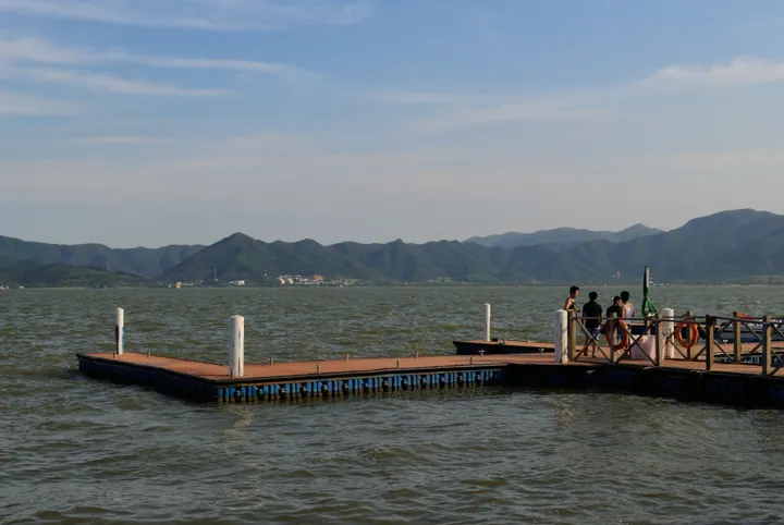 A wooden dock extending into a lake with mountains along the far shore