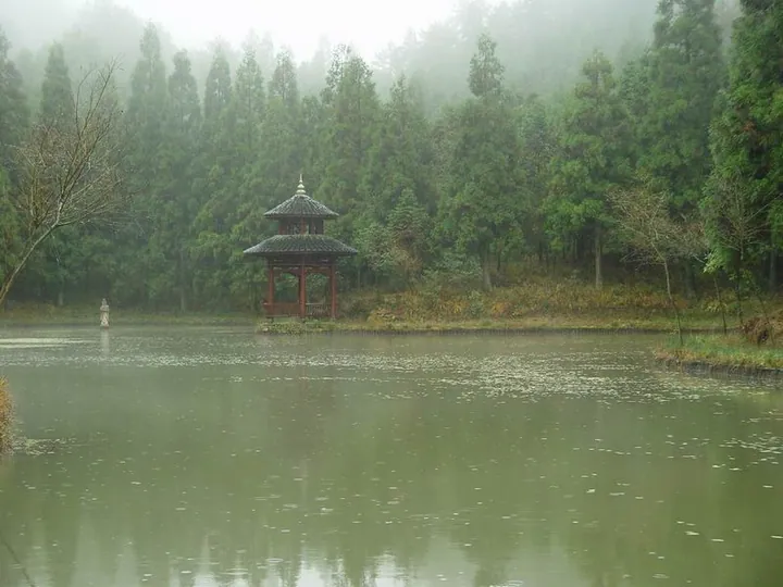 A misty forest lake with a small pavilion at the Hometown of Liu Bowen scenic area