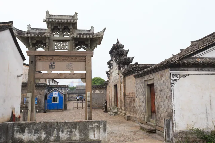 Carved stone memorial archway leading into a traditional courtyard lane