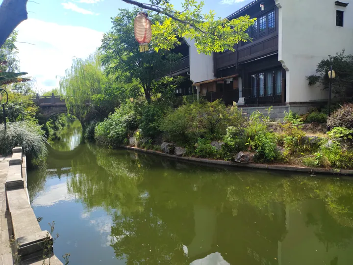 Canal with a stone bridge and willow trees in Meicheng Ancient Town, Jiande