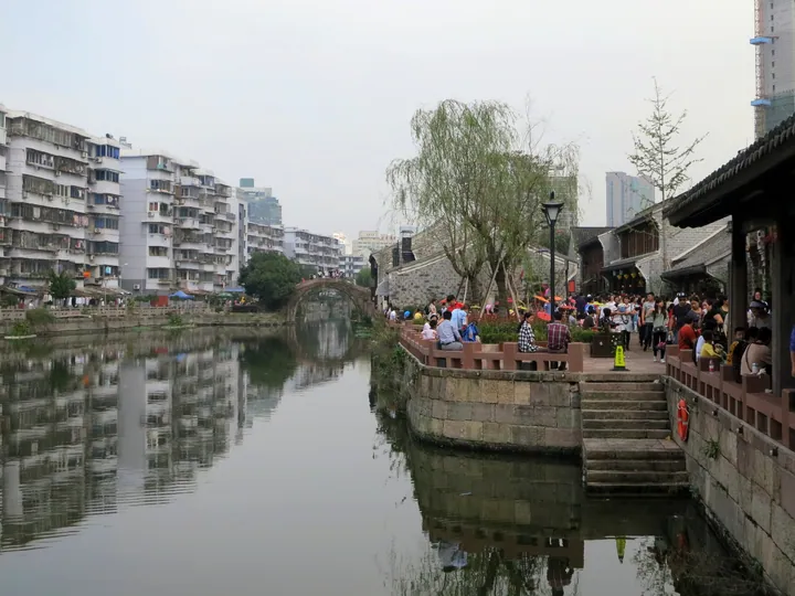 Old stone arch bridge over a canal lined with traditional Chinese buildings