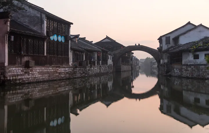 Arched stone bridge reflected in a canal in Nanxun ancient town at sunrise