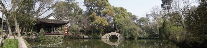 Chinese garden with a pond, pavilion and arched stone bridge