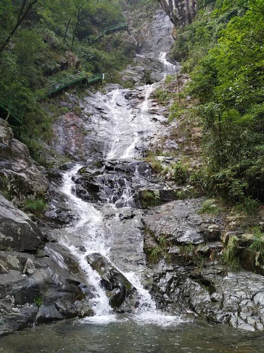 Waterfall over rocks in a forested mountain canyon