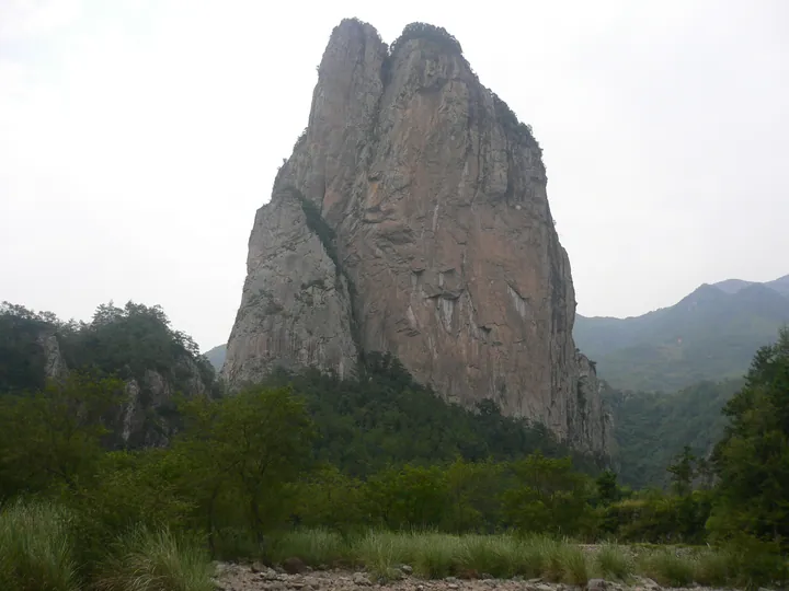 A tall twin rock spire rising above a forested valley