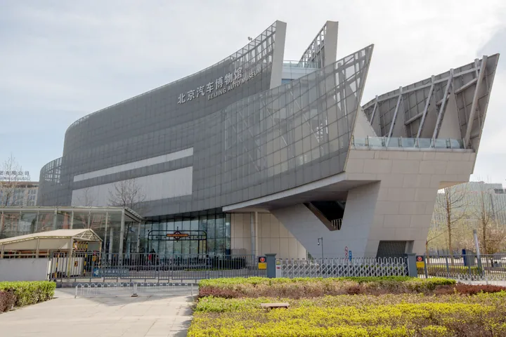 Modern curved glass and steel facade of the Beijing Auto Museum with its name in Chinese and English