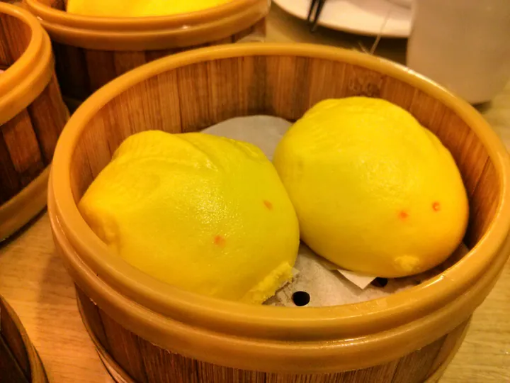 Two goldfish-shaped custard buns (liu sha bao) in a bamboo steamer