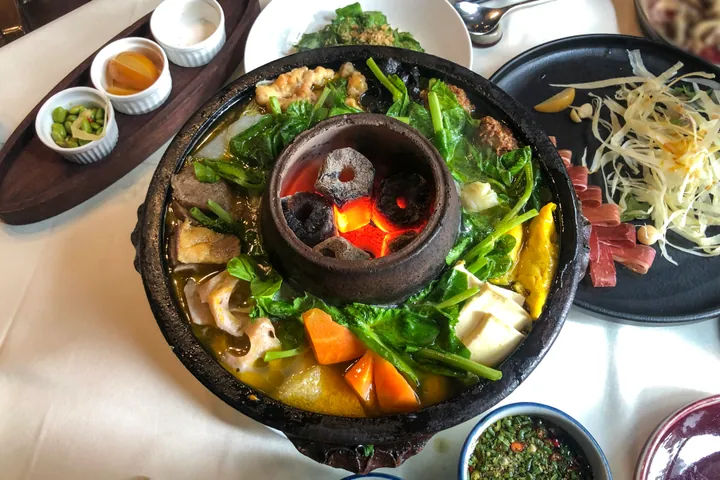 Clay-pot hotpot with meat, tofu and vegetables around a charcoal center