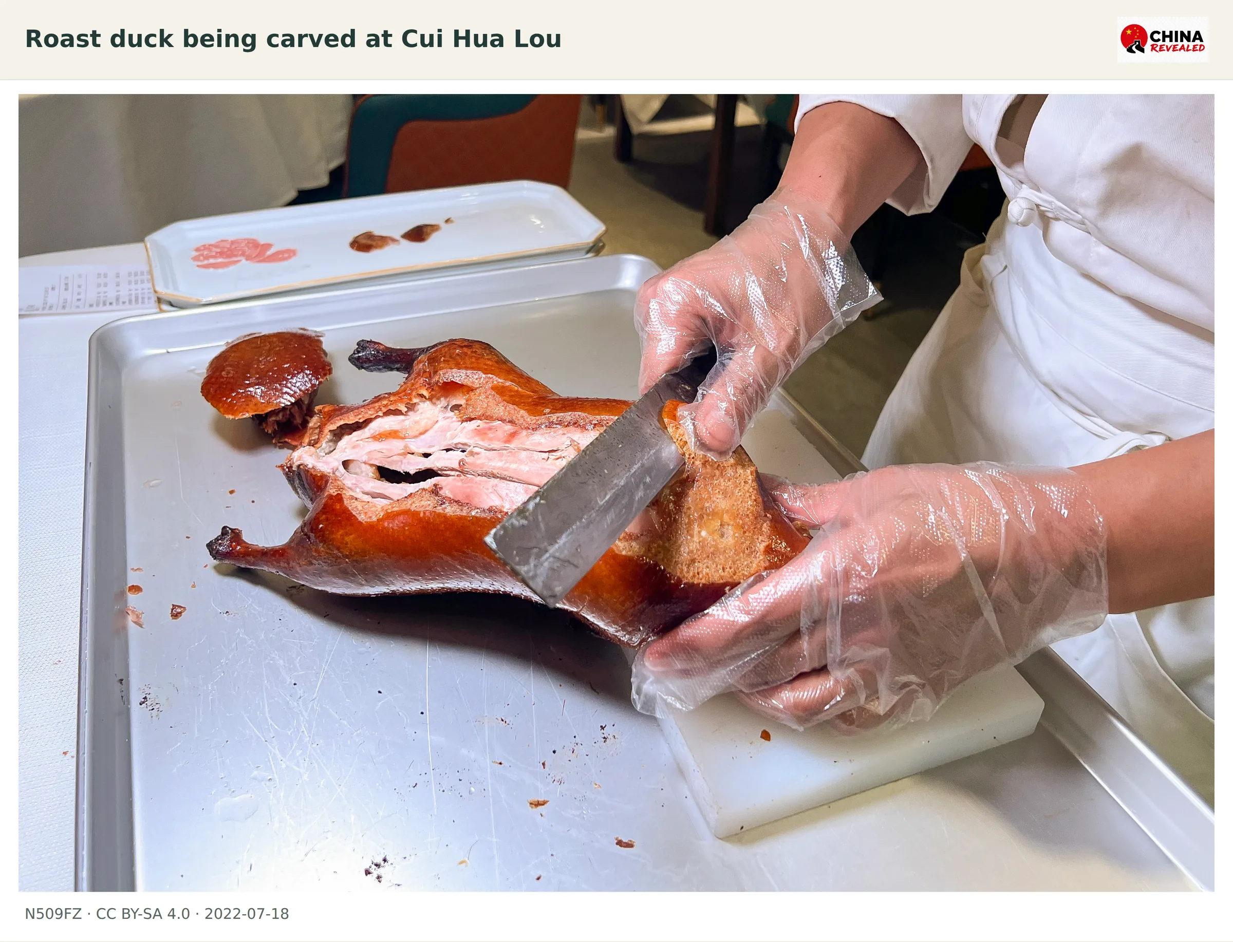 A chef carving lacquered Beijing roast duck at a table in Dongzhimen