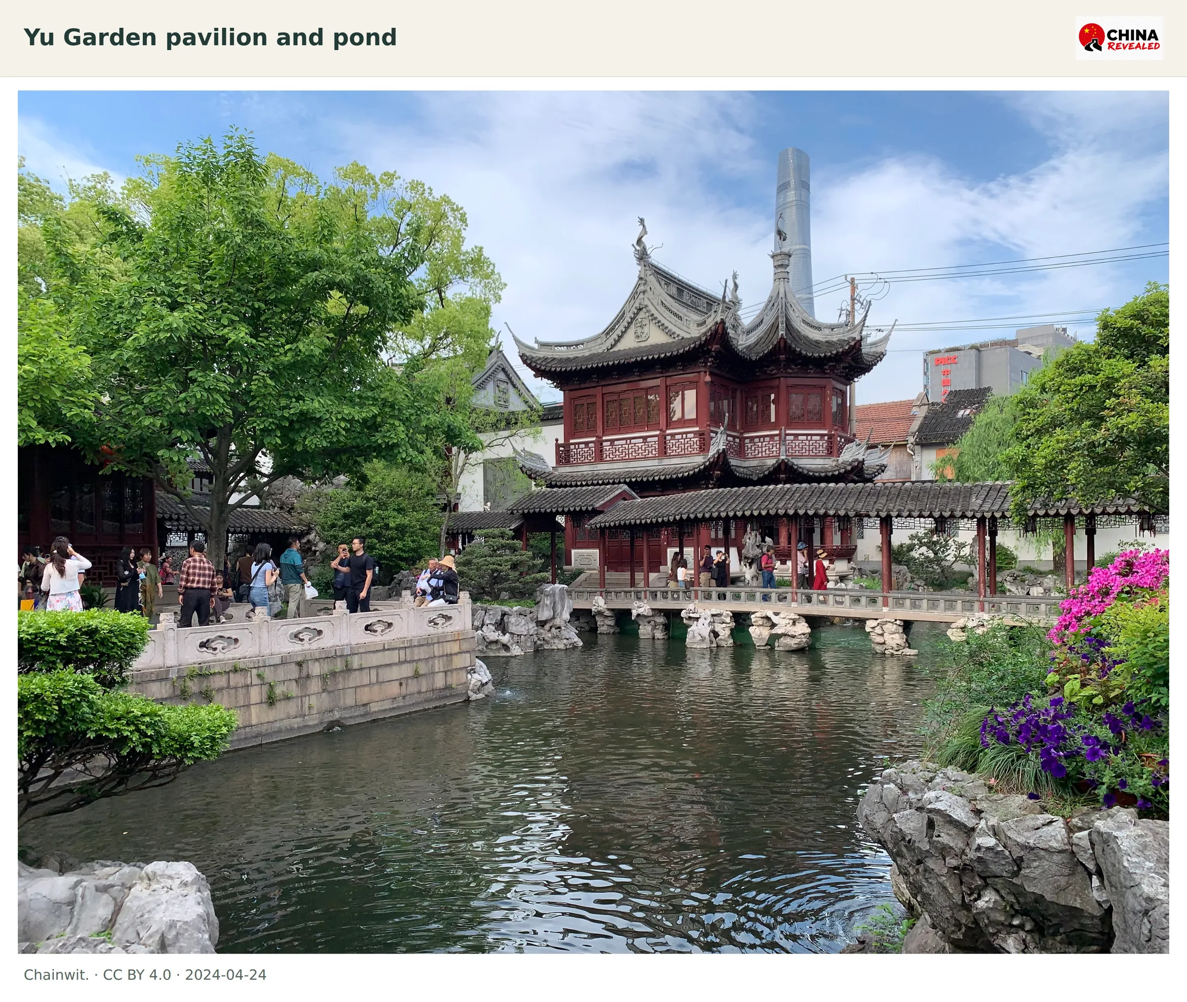Red pavilion, rockery, pond and cloister inside Yu Garden with Shanghai Tower visible behind