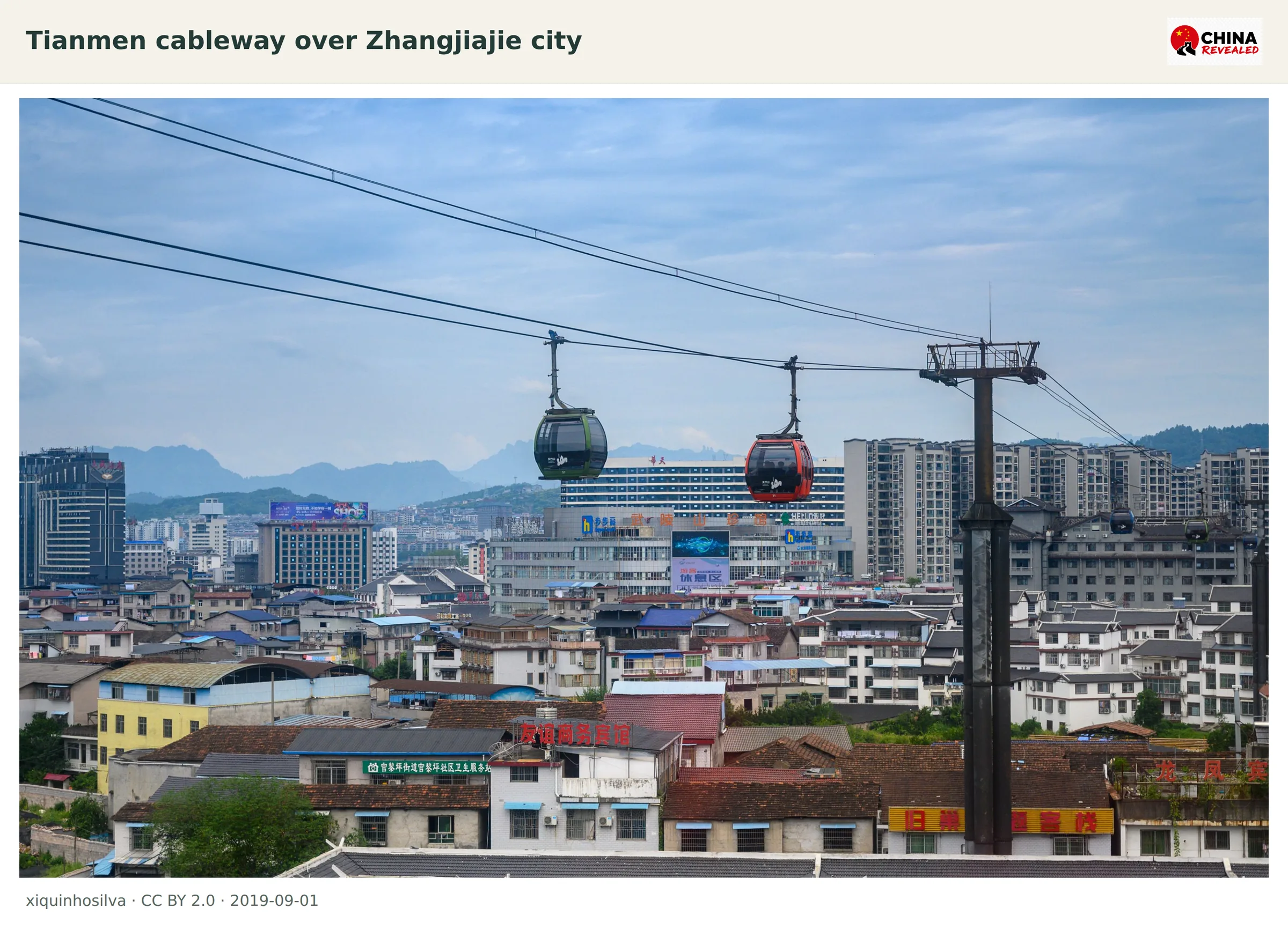 Cableway cabins crossing above Zhangjiajie city with mountains behind